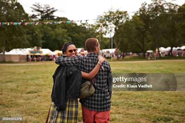 happy woman walking with arm around boyfriend at park - music festival field stock pictures, royalty-free photos & images