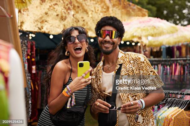 cheerful couple trying sunglasses at market stall - product photo shoot stock pictures, royalty-free photos & images