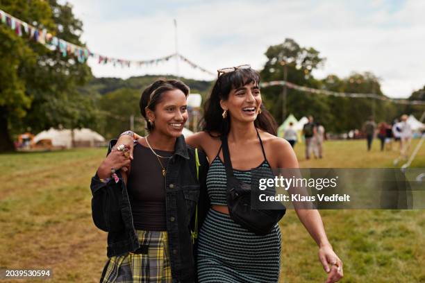 happy female friends with arms around walking at park - denim coat stock pictures, royalty-free photos & images