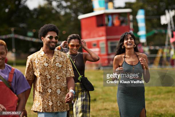 happy male and female friends walking at park - music festival field stock pictures, royalty-free photos & images