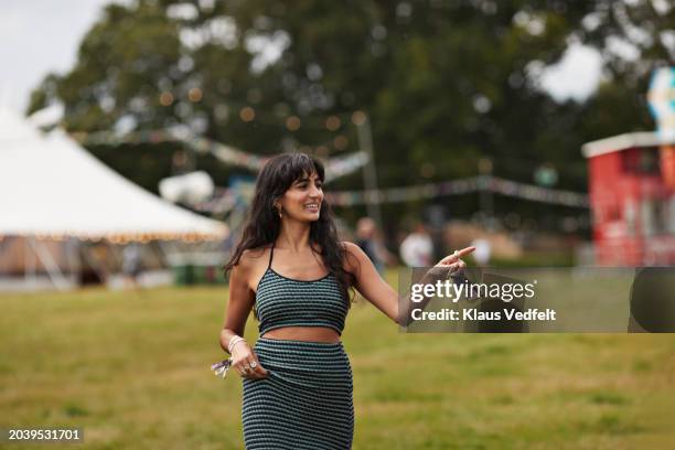 smiling woman pointing away while walking at park - music festival field stock pictures, royalty-free photos & images