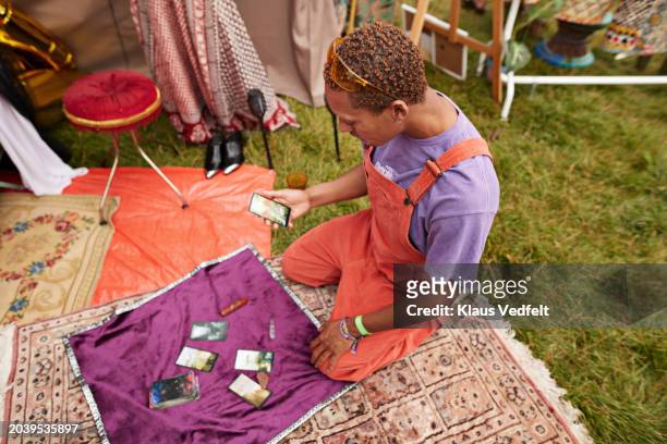 man looking at tarot cards kneeling on blanket - enlightenment stock pictures, royalty-free photos & images