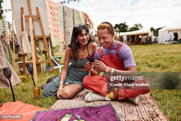 happy couple looking at tarot cards sitting on blanket - cross legged stock pictures, royalty-free photos & images