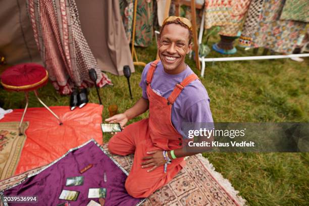 happy man looking at tarot cards kneeling on blanket - enlightenment stock pictures, royalty-free photos & images