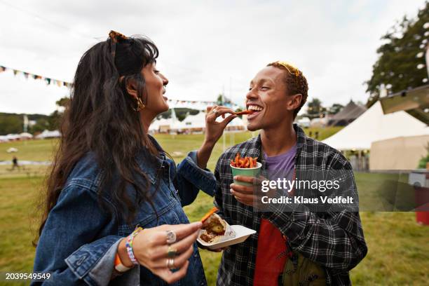 happy woman feeding street food to boyfriend - partage photos et images de collection