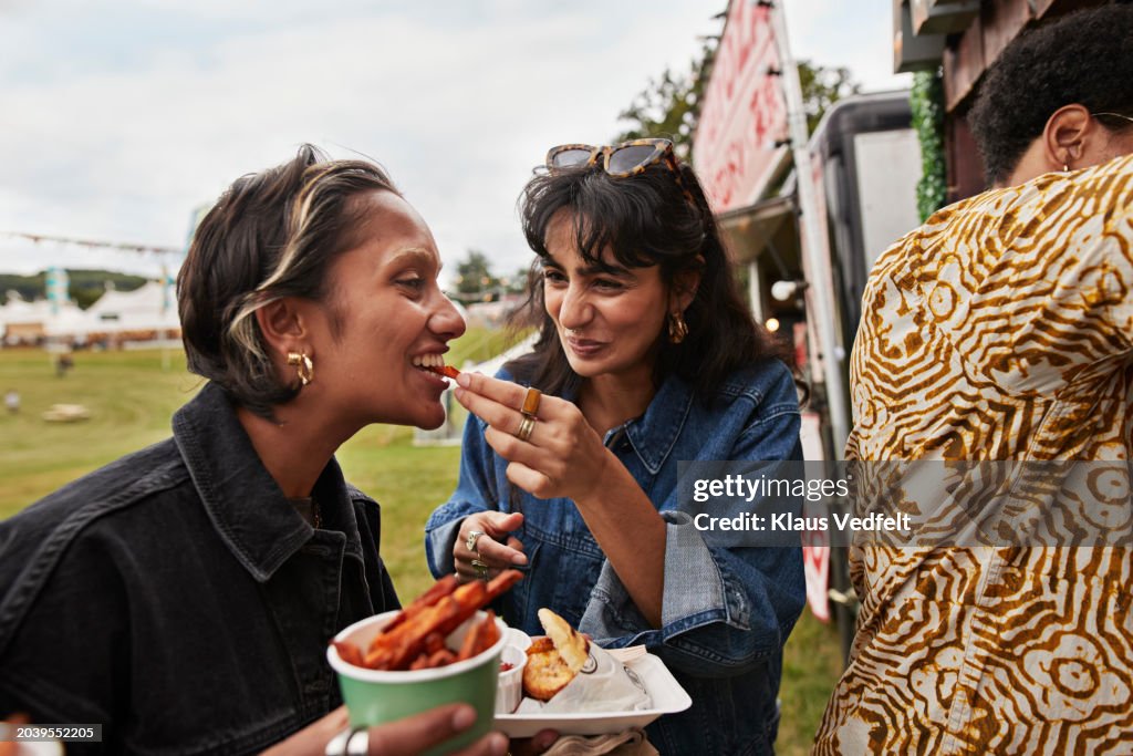 Happy woman feeding female friend