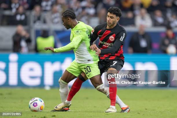 Ridle Baku of VfL Wolfsburg is tackled by Omar Marmoush of Eintracht Frankfurt during the Bundesliga match between Eintracht Frankfurt and VfL...