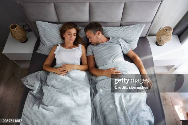 above view of relaxed couple sleeping in bed. - pyjamas stock pictures, royalty-free photos & images