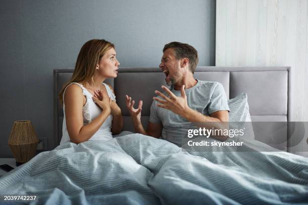 wütendes paar, das sich morgens im bett streitet. - kommunikationsproblem stock-fotos und bilder
