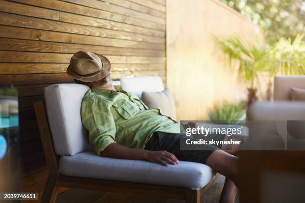 erschöpfter mann, der ein nickerchen auf dem sofa auf der terrasse macht. - müde frühling stock-fotos und bilder