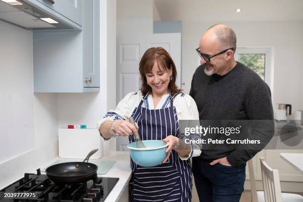 cheerful husband and wife preparing food together in a domestic kitchen - man in wife beater stock pictures, royalty-free photos & images