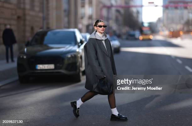 Sophia Geiss seen wearing Saint Laurent black sunglasses, silver earrings, COS dark grey oversized short wool coat, Arket grey cotton hooded zip...