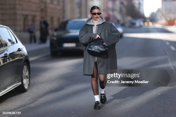 Sophia Geiss seen wearing Saint Laurent black sunglasses, silver earrings, COS dark grey oversized short wool coat, Arket grey cotton hooded zip...