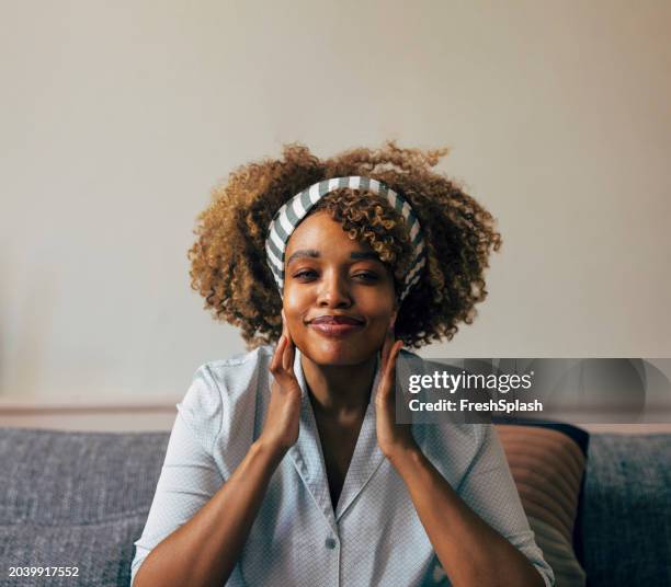 relaxed young woman enjoying a peaceful moment at home, happy and content - hair band stock pictures, royalty-free photos & images