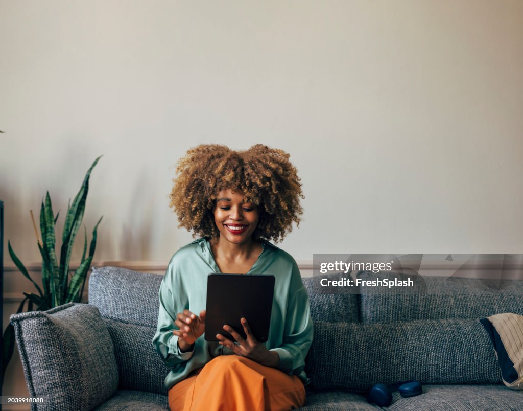 Happy African American Woman Using Tablet on a Cozy Sofa at Home