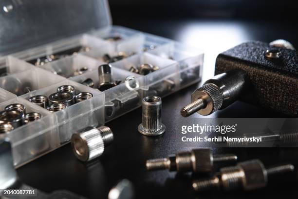 threaded insert riveter gun kit. setting tool, nosepieces and inserts, for all types of rivets, including threaded rivet nuts, pliers. black background, selective focus - nut fastener - fotografias e filmes do acervo