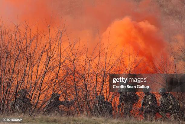 Soldiers of the United Kingdom's 2nd Battalion Royal Anglian infantry unit emerge from orange smoke as they storm an enemy position in a simulated...