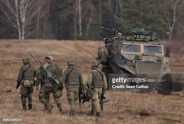 Spanish troops walk past a British Foxhound mechanized infantry vehicle as they take part in the NATO "Brilliant Jump" military exercises on February...
