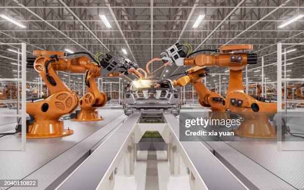 assembly line of robots welding car body - auto bauen stock-fotos und bilder