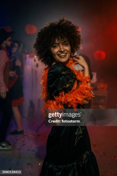 charming young woman dancing in costume during a fun halloween party - boa persoonlijk accessoire stockfoto's en -beelden