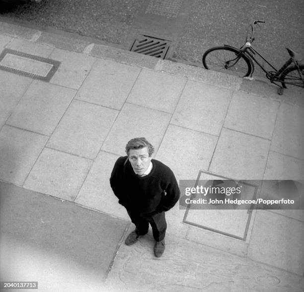 View from above of English photographer Antony Armstrong-Jones posed with his camera on a street in London in 1958. Armstrong-Jones would go on to...