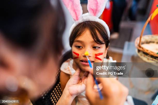 girl with bunny painting on face during easter holiday at home - face paint stock pictures, royalty-free photos & images