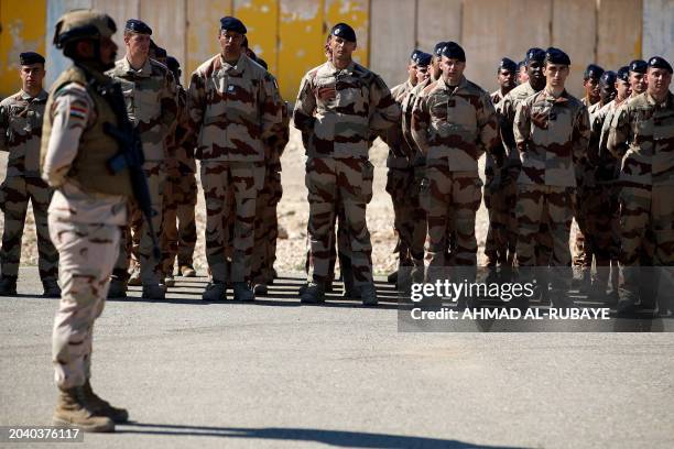 French soldiers stand at ease during the graduation ceremony of Iraqi soldiers from the new 'desert battalion' special forces, after months of...