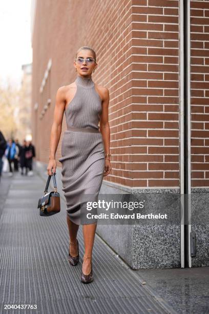 Caroline Daur wears sunglasses, earrings, a gray ribbed wool turtleneck sleeveless midi dress , a leather bag, shoes, outside Fendi, during the Milan...