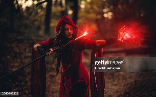 evil witch practicing magic in the forest using a magic cane at night - witch wand stock pictures, royalty-free photos & images
