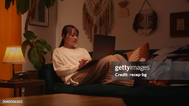 woman using her laptop in the living room at home at night - entrepreneur stockfoto's en -beelden