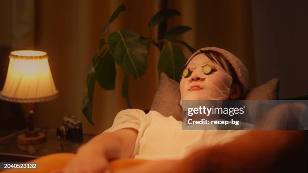 frau genießt ihre zeit und macht hautpflege im wohnzimmer zu hause - warmes licht stock-fotos und bilder