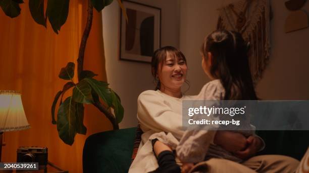 mother spending time with her daughter in the living room at home - warm light stock pictures, royalty-free photos & images