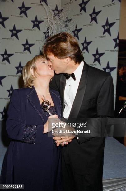 English television presenters Judy Finnigan and Richard Madeley share a kiss while holding their award for Most Popular Daytime Programme at the 5th...