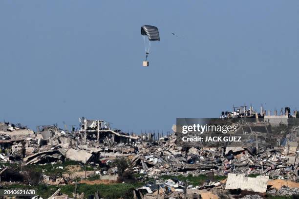 Picture taken from a position in southern Israel on February 29 shows a parachute belonging to the Israeli Army dropping a box over destroyed...