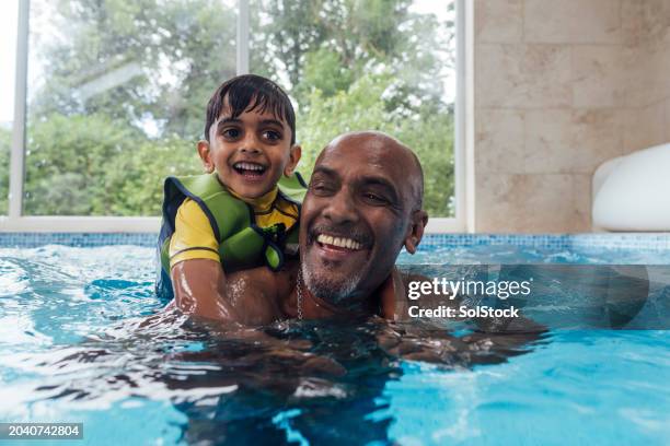 grandad and grandson playfully swimming - kid swimming stock pictures, royalty-free photos & images
