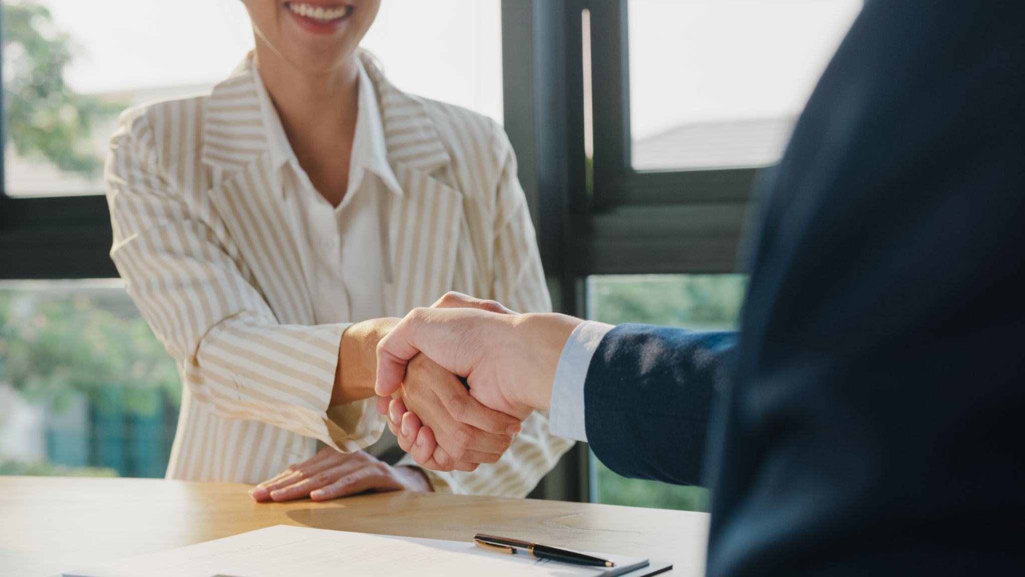 Closeup of young Asian businessman sign a contract investment professional document agreement and shake hands at office. Businesspeople in workplace. Closeup of young Asian businessman sign a contract investment professional document agreement and shake hands at office. Businesspeople in workplace.