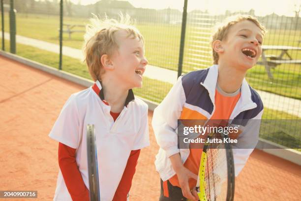 two young boys holding tennis rackets smiling - holding tennis racquet stock pictures, royalty-free photos & images