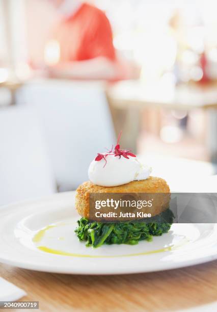 hake fishcake on spinach with poached egg - fish cakes stock pictures, royalty-free photos & images