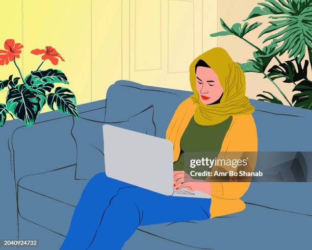 young woman in hijab working form home at laptop on living room sofa - headscarf stock illustrations