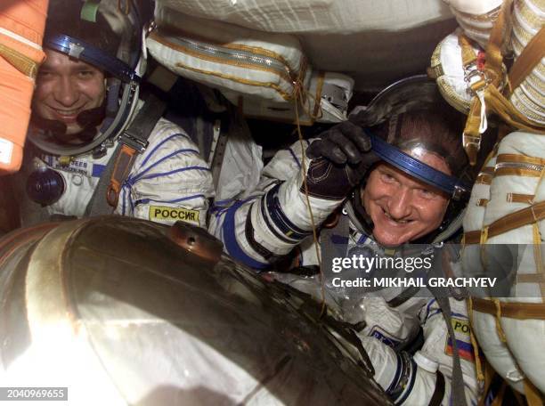 Russian cosmonauts Viktor Afanasyev and Konstantin Kozeyev gesture inside the capsule after landing near the village of Zhayrem, some 400 km south...