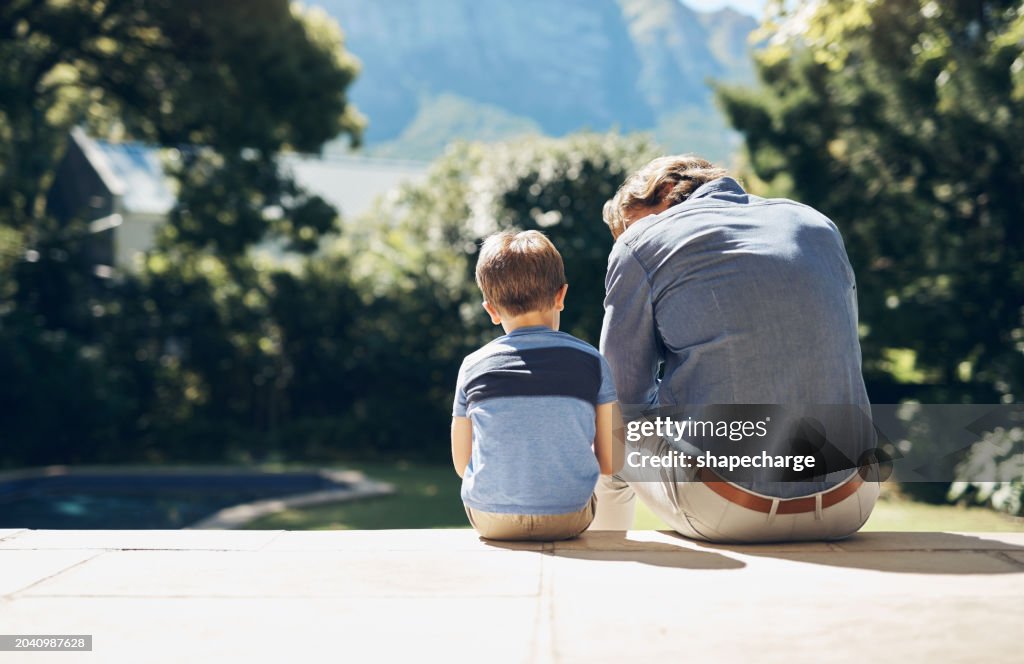 Father sitting and comforting sad son with autism, mental disorder and depression on garden step backyard patio. Back view of caring, loving and kind single parent supporting, comforting and talking