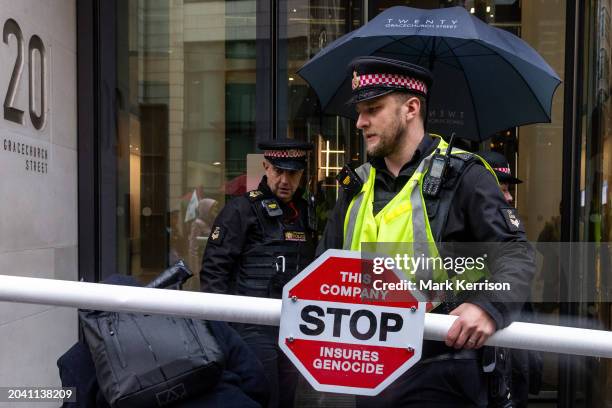 City of London Police officers move a mock Israeli checkpoint erected by climate and human rights activists outside the offices of AXA UK plc during...