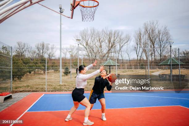 female friends playing one on one basketball - shooting baskets stock pictures, royalty-free photos & images