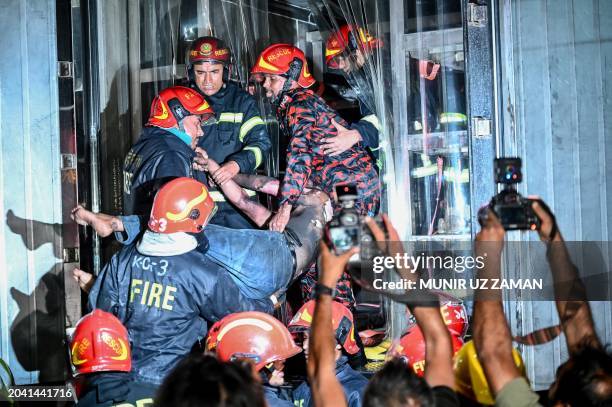 Graphic content / Firefighters carry an injured person during rescue operations following a fire in a commercial building that killed at least 43...