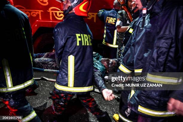 Firefighters carry an injured person during rescue operations following a fire in a commercial building that killed at least 43 people, in Dhaka, on...