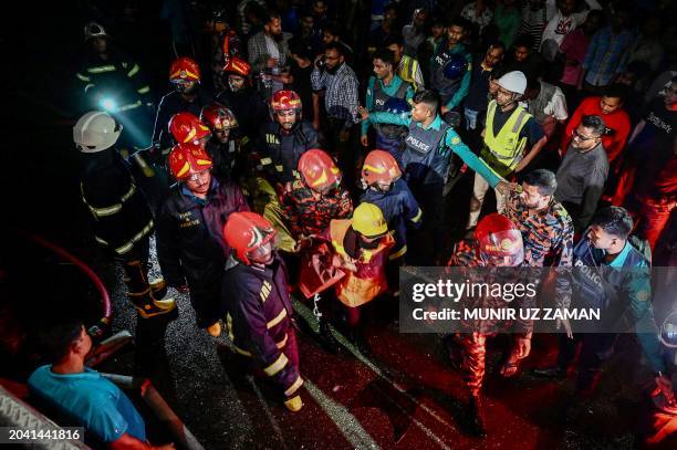 Graphic content / Firefighters carry an injured person during rescue operations following a fire in a commercial building that killed at least 43...