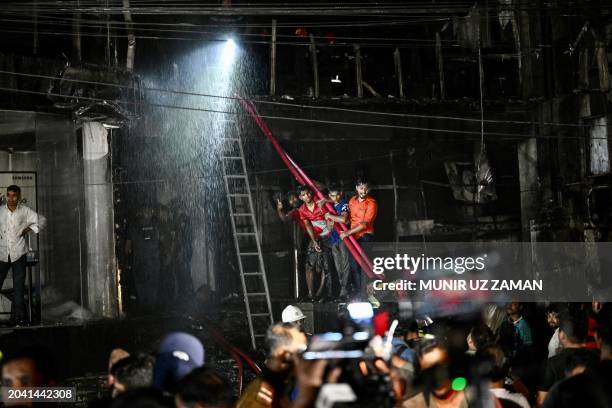 Members of the publichelp as firefighters work to extinguish a fire in a commercial building that killed at least 43 people, in Dhaka, on February...