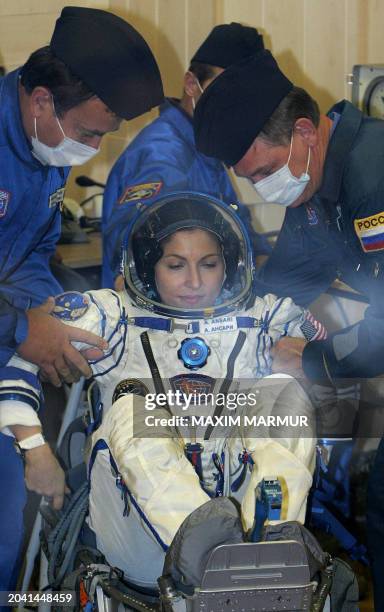 Russian specialists help the world's first woman space tourist Anousheh Ansari put on a spacesuit before boarding a space ship at the Baikonur...