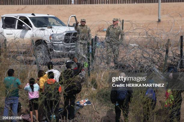 Texas National Guard agents prevent migrants from Venezuela from crossing a barbed wire fence to at the El Paso Sector Border after crossing the Rio...