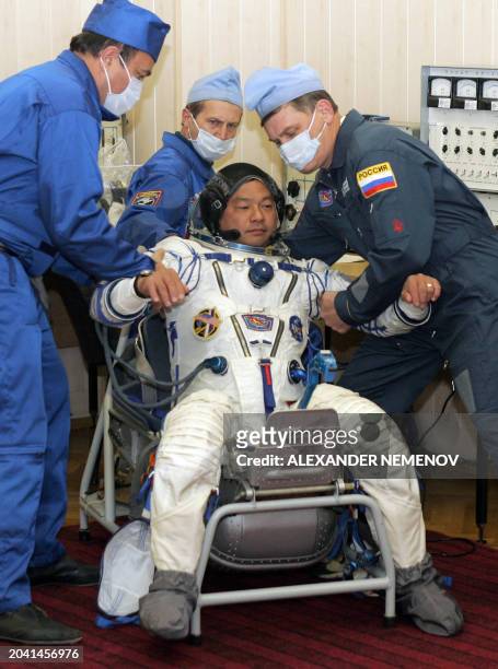 Staff members check the space suit of US astronaut Leroy Chiao before leaving for the launch pad of Russian leased Baikonur cosmodrome in Kazakhstan,...